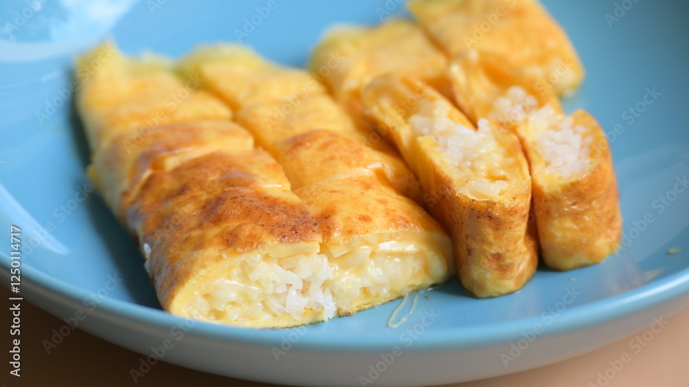 roll omelette stuffed with chesse and rice on blue plate, delicious food in the morning roll omelette stuffed with chesse and rice on blue plate, delicious food in the morning