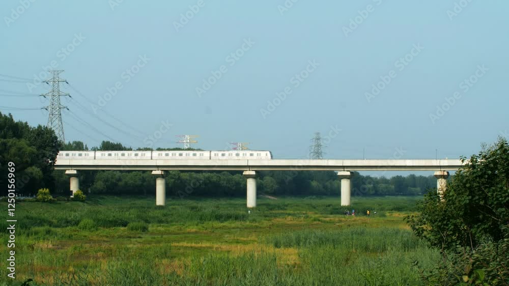 Beijing Subway City Railway Shuttle crosses bridge over lush green landscape during sunny day Beijing Subway City Railway Shuttle crosses bridge over lush green landscape during sunny day