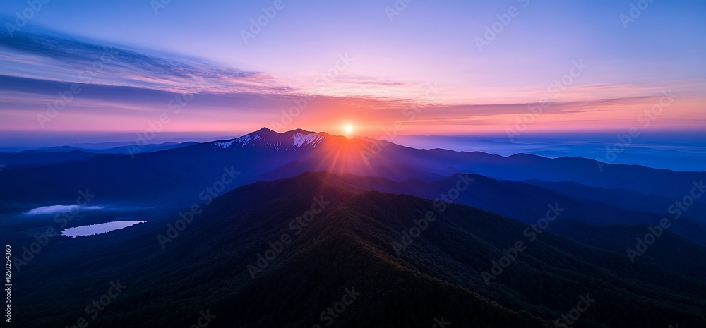 Vibrant sunburst paints the misty mountain peaks at dawn, a serene landscape in hues of purple and blue