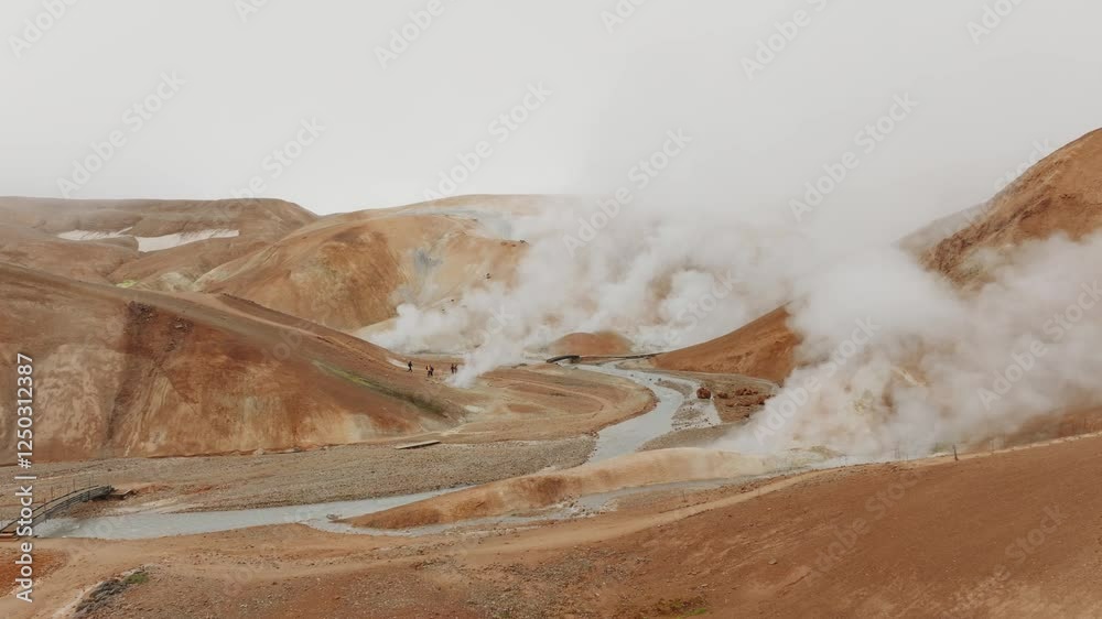 50fps aerial shot of Kerlingarfjöll’s geothermal area. Steam rises from vents amidst orange hills, with visitors exploring the rugged terrain. Ideal for nature, travel, and adventure projects.