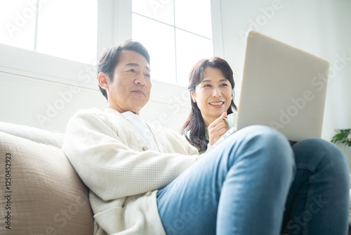 パソコンを見ながら会話する50代夫婦
