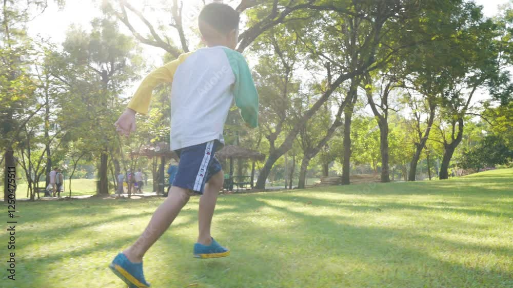 Happy little school boy enjoy run on green meadow grass sunset light city park slow motion Happy little school boy enjoy run on green meadow grass sunset light city park slow motion