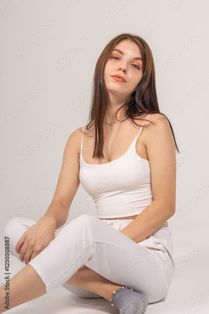 Young brunette sitting on a white background. Copyspace Young brunette sitting on a white background. Copyspace