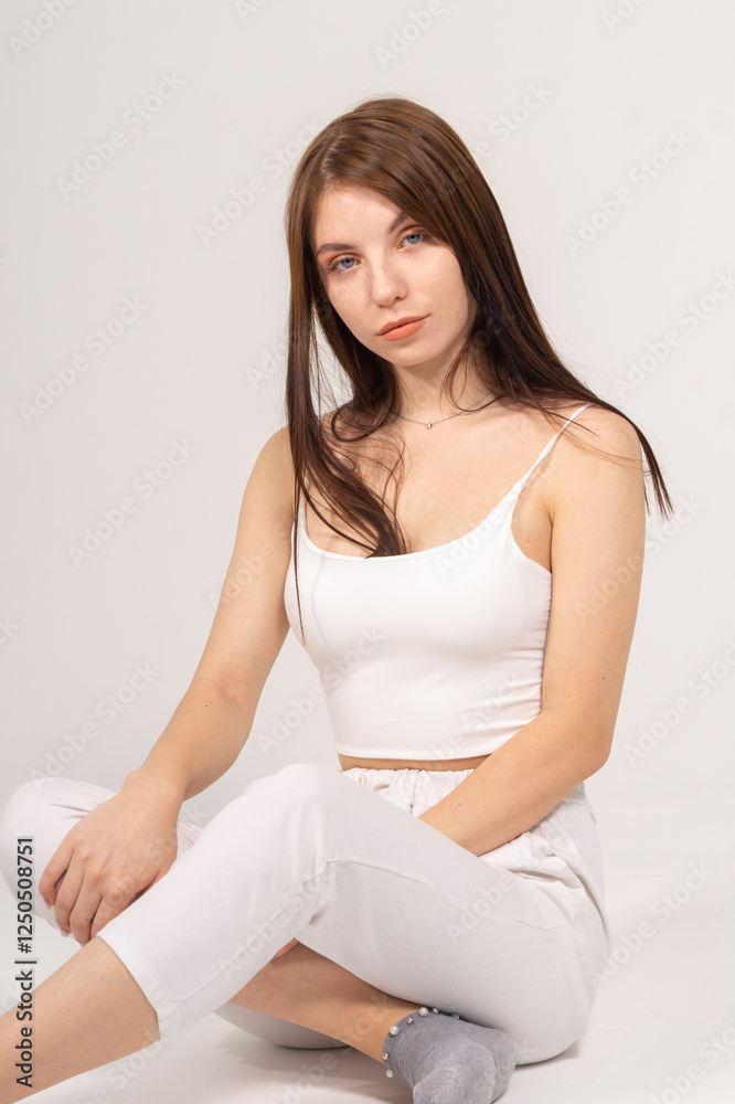 Young brunette sitting on a white background. Copyspace Young brunette sitting on a white background. Copyspace