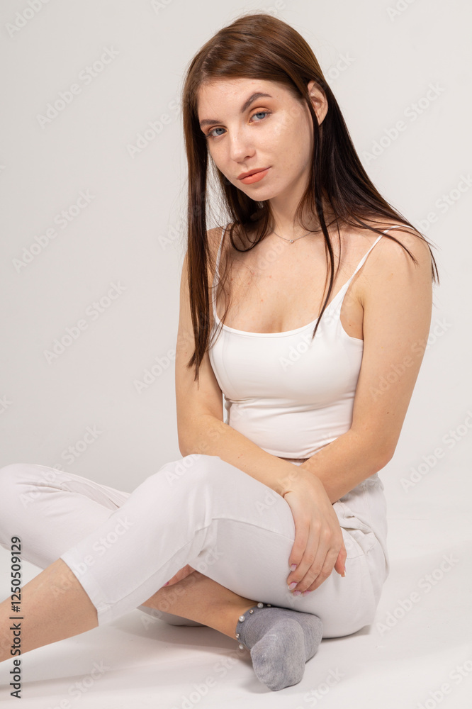 Young brunette sitting on a white background. Copyspace Young brunette sitting on a white background. Copyspace