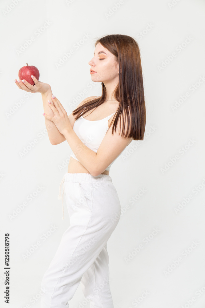 Young brunette holding a red apple standing on a white background. Copyspace Young brunette holding a red apple standing on a white background. Copyspace