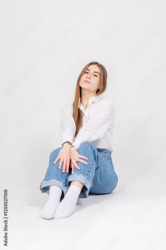 Cute young girl sitting on a floor, white background, copyspace Cute young girl sitting on a floor, white background, copyspace