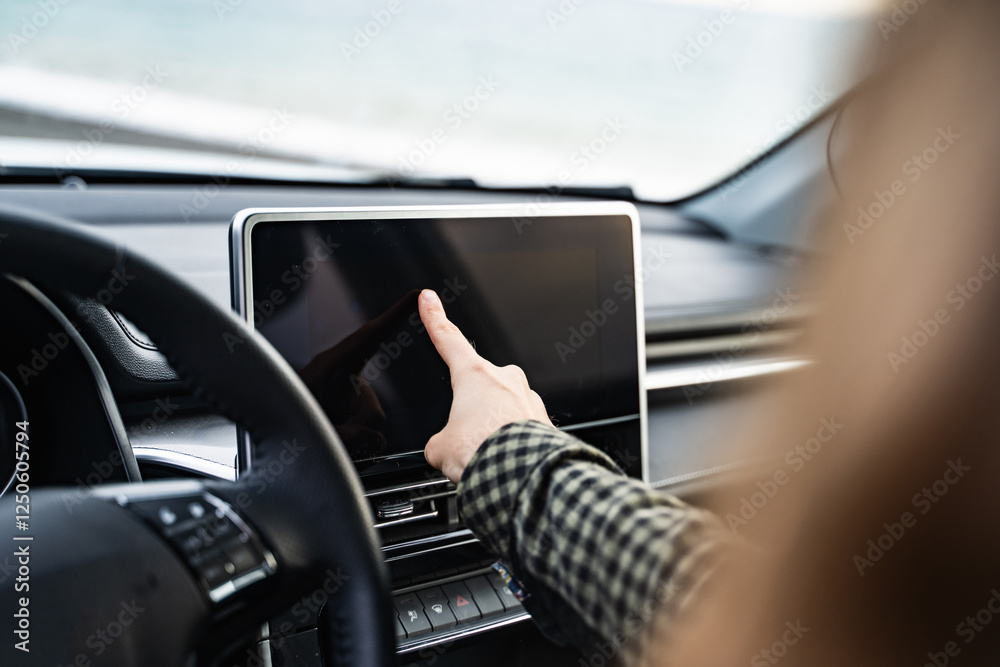 Side view of an unrecognizable woman using a GPS navigation system while driving her car. Female driver touching modern car dashboard. Screen multimedia system in automobile. Closeup. Side view of an unrecognizable woman using a GPS navigation system while driving her car. Female driver touching modern car dashboard. Screen multimedia system in automobile. Closeup.