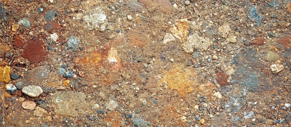 Textured natural ground surface with colorful stones and gravel in earthy tones, suitable for backgrounds or landscaping projects.