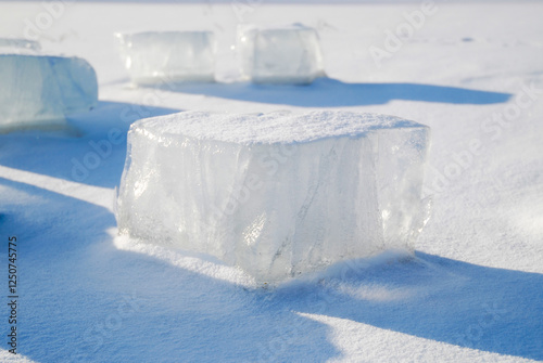 Clear ice blocks resting on fresh snow, illuminated by winter sunlight, casting long shadows and creating a crisp, serene, and minimalist cold-weather scene photo