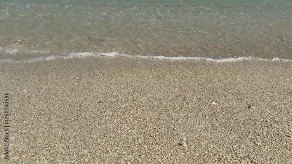 A peaceful beach scene featuring clear, shallow seawater gently washing over a sandy shore with small pebbles. The sunlight creates a shimmering effect on the water’s surface. Horizontal, no sound A peaceful beach scene featuring clear, shallow seawater gently washing over a sandy shore with small pebbles. The sunlight creates a shimmering effect on the water’s surface. Horizontal, no sound