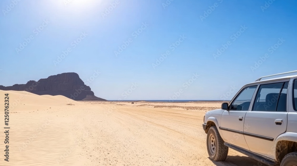 A silver SUV parked on a sandy landscape under a clear blue sky. A silver SUV parked on a sandy landscape under a clear blue sky.