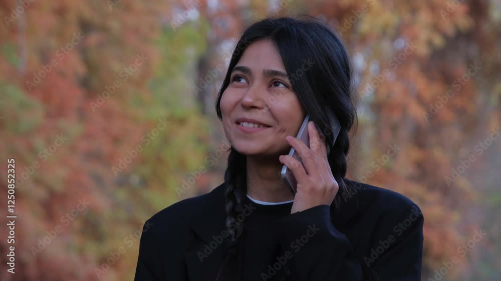 Young woman in elegant clothes enjoys a phone call, her connection seamless amidst the beauty of the park. Young woman in elegant clothes enjoys a phone call, her connection seamless amidst the beauty of the park.