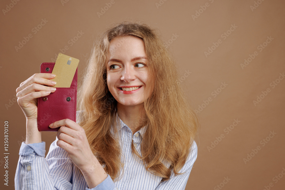 Smiling woman takes out gold bank card from red wallet on uniform beige background, online payments, virtual money, keeping money in bank Smiling woman takes out gold bank card from red wallet on uniform beige background, online payments, virtual money, keeping money in bank