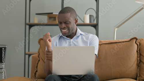 African Man with Wrist Pain Using Laptop at Home