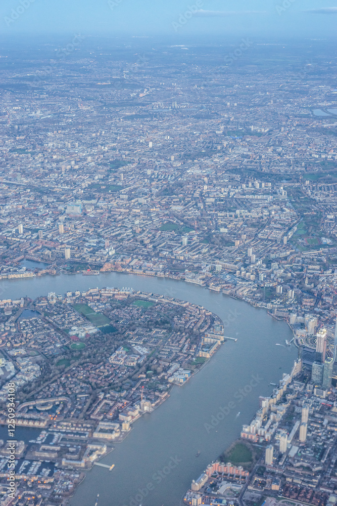 Aerial view of London through early morning clouds with Thames river flowing at golden hour sunrise near Tower Bridge