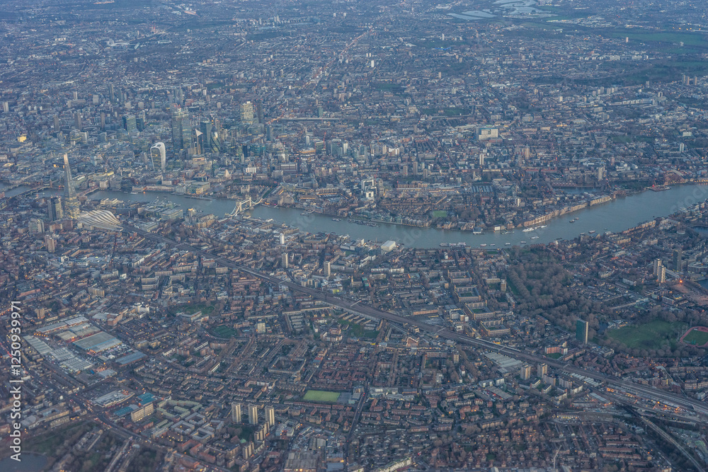 Aerial view of London through early morning clouds with Thames river flowing at golden hour sunrise near Tower Bridge