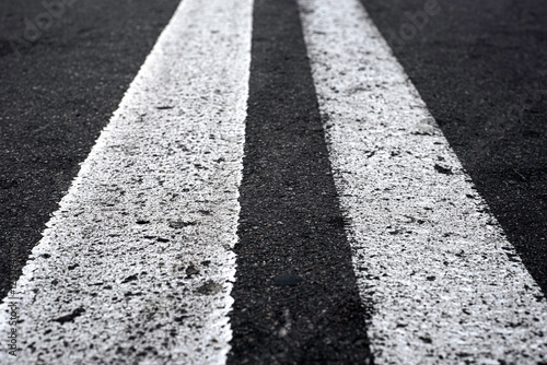 Double solid line on the road. Two white stripes on the asphalt road. Perspective view of the white lines. Empty road.