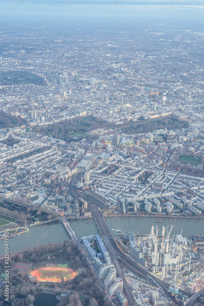 Aerial view of London outskirts suburbs through early morning clouds with Thames river flowing at golden hour sunrise near industrial area
