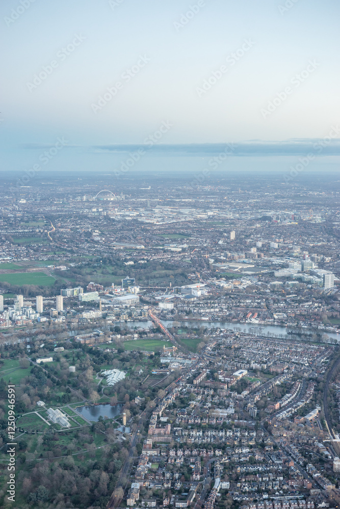 Aerial view of London outskirts suburbs through early morning clouds with Thames river flowing at golden hour sunrise near industrial area Aerial view of London outskirts suburbs through early morning clouds with Thames river flowing at golden hour sunrise near industrial area