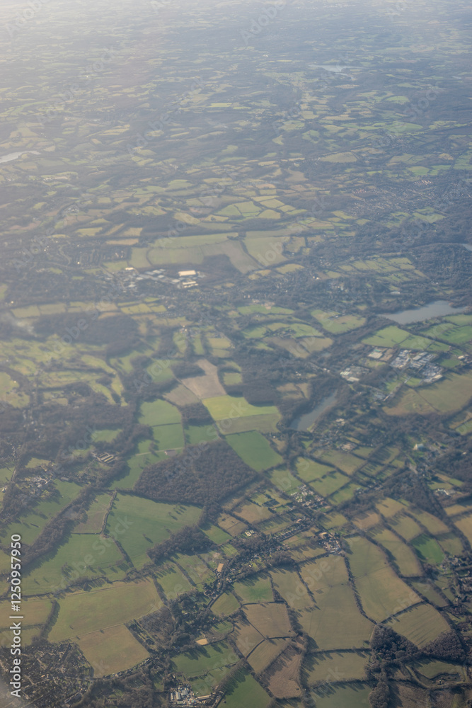 Aerial view of London outskirts lush green fields from an aeroplane window