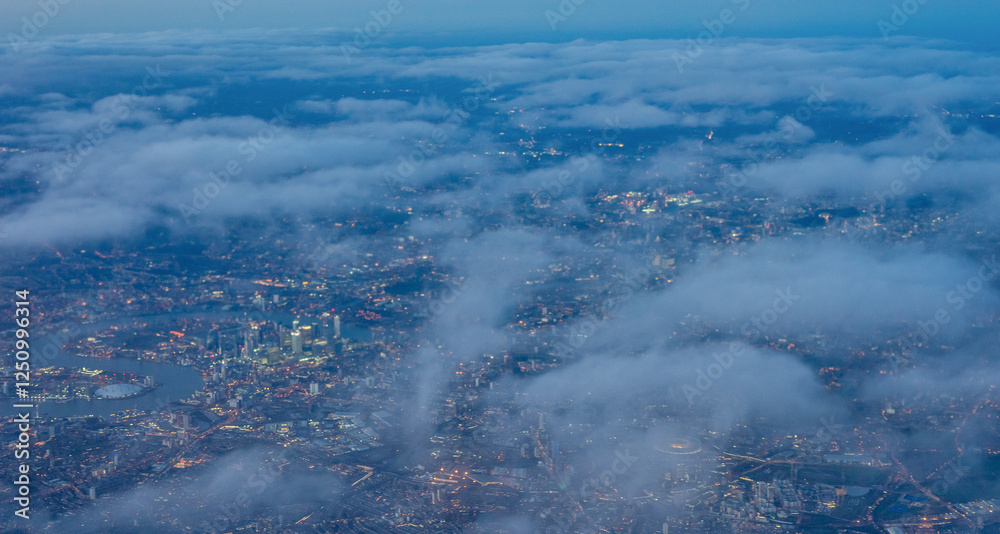 Aerial view of London through early morning clouds with Thames river flowing at golden hour sunrise