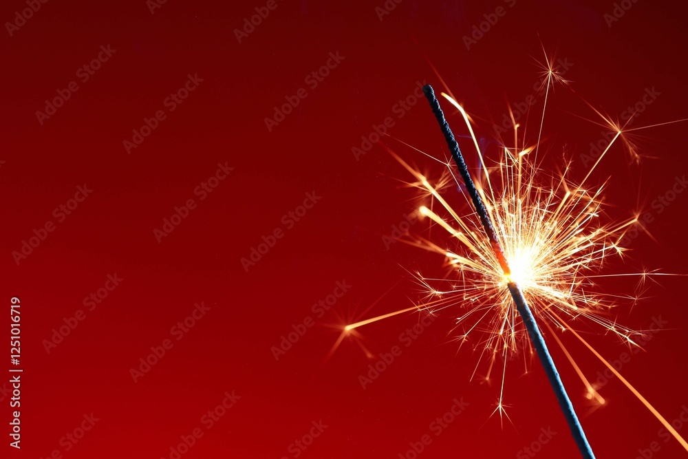 Obraz premium Bright burning sparkler on red background, closeup. Space for text
