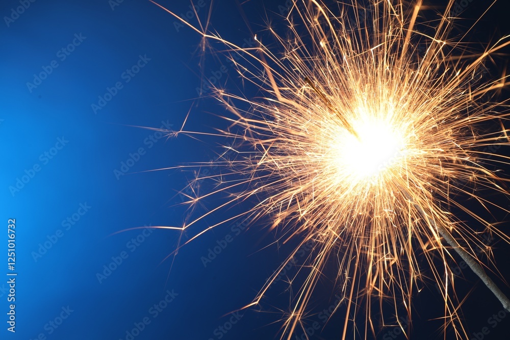 Obraz premium Bright burning sparkler on blue background, closeup. Space for text