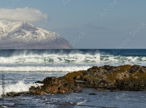 Russia. The Far East. The Kuril Islands. View of the basalt rock outcrops of volcanic origin on the sea sandy shore of Iturup island.