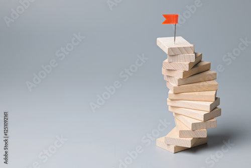 Wooden pieces arranged to a winding wooden staircase to success, an effort that seems to be stuck in place but climbing to the top, goal setting, consistency behaviors concept