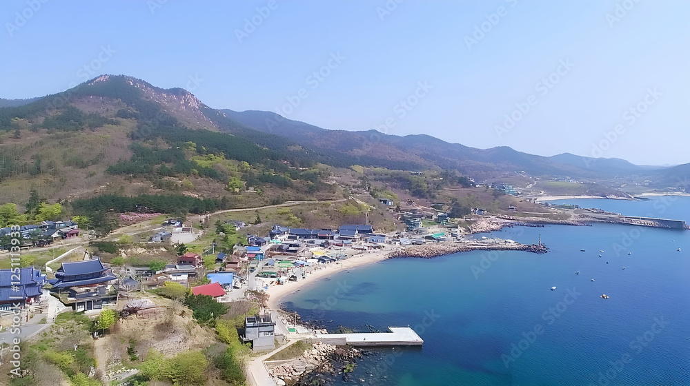 Fototapeta premium Aerial view of coastal village nestled beside mountains. Possible use Stock photo for travel guides, tourism websites, or showcasing Asian villages