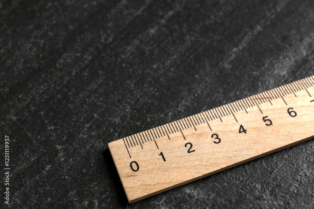 One wooden ruler on black table, closeup. Space for text One wooden ruler on black table, closeup. Space for text