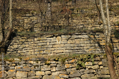 In eine Trockensteinmauer ist ein Gesicht aus Stein integriert