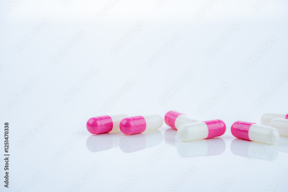 Pink-white antibiotic capsules spread on white background. Prescription drug. Antibiotic resistance in modern medicine. Healthcare and pharmaceutical industry. Medical care, pharmaceutical research. Pink-white antibiotic capsules spread on white background. Prescription drug. Antibiotic resistance in modern medicine. Healthcare and pharmaceutical industry. Medical care, pharmaceutical research.