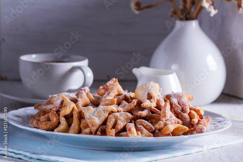 Traditional Maslenitsa dessert angel wings served with coffee on a light background.