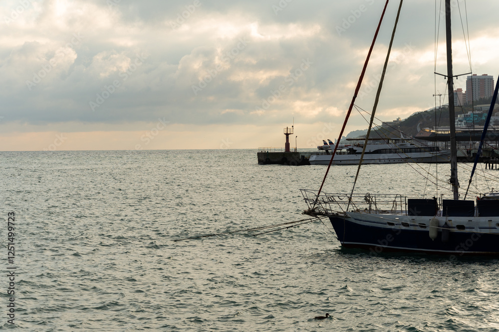 view from the shore of a yacht and the sea at sunset view from the shore of a yacht and the sea at sunset