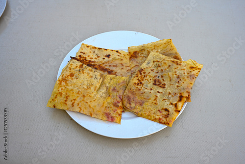 Freshly baked appetizing Turkish tortillas - Gozleme with spinach, cheese  on a white board. Space for text. Handmade Turkish traditional pastries. Ispanakli, otlu peynirli gozleme. Tahinli Katmer photo