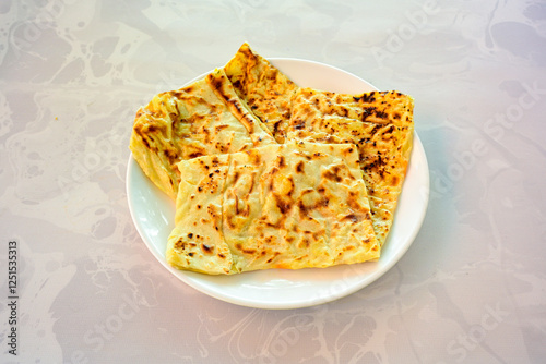Freshly baked appetizing Turkish tortillas - Gozleme with spinach, cheese  on a white board. Space for text. Handmade Turkish traditional pastries. Ispanakli, otlu peynirli gozleme. Tahinli Katmer photo
