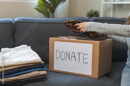 Billede på lærred Recycling, Donation for poor, asian young woman, girl sitting pack object at home, putting on stuff into donate box with second hand clothes, charity helping and needy people