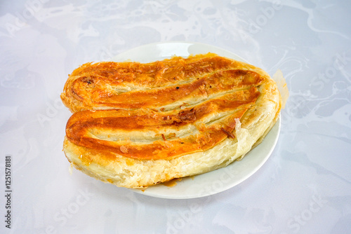 Turkish style meat stuffed filo dough borek served kol boregi. Cheese and minced pie are sliced on a marble background.  Avci boregi.Turkish name: Kol Boregi. Kiymali, peynirli su boregi. photo