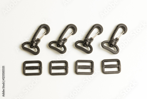 Set of black plastic swivel hooks and strap adjusters for bag accessories, isolated on white.