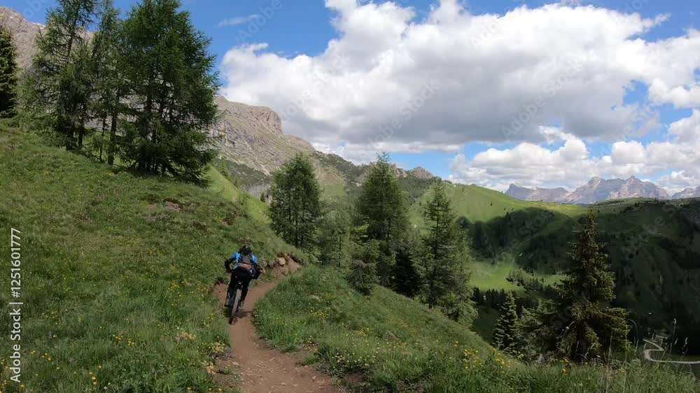A sunlit path winds through green fields, offering bikers a peaceful ride under the clear skies of the Dolomite region. A sunlit path winds through green fields, offering bikers a peaceful ride under the clear skies of the Dolomite region.