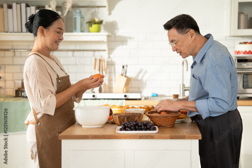 Asian senior couple cooking breakfast in the kitchen. husband helping wife on the morning weekend. Retired people enjoying lifestyle at the preparing counter Asian senior couple cooking breakfast in the kitchen. husband helping wife on the morning weekend. Retired people enjoying lifestyle at the preparing counter