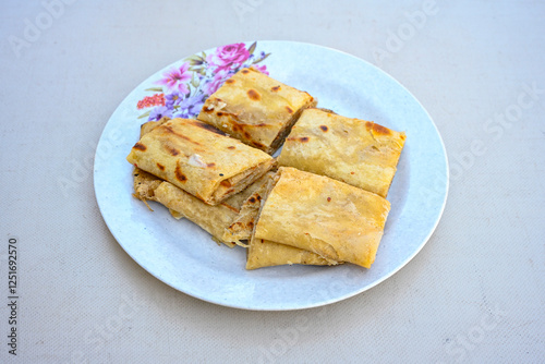 Freshly baked appetizing Turkish tortillas - Gozleme with spinach, cheese  on a white board. Space for text. Handmade Turkish traditional pastries. Ispanakli, otlu peynirli gozleme. Tahinli Katmer photo