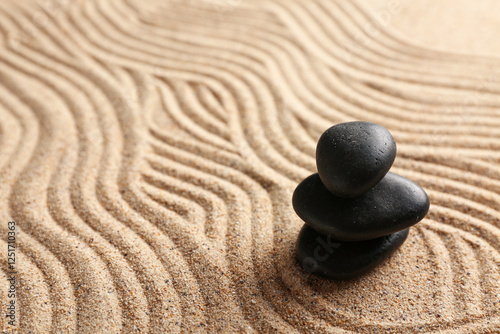 Photography Black stones on sand with lines. Zen concept