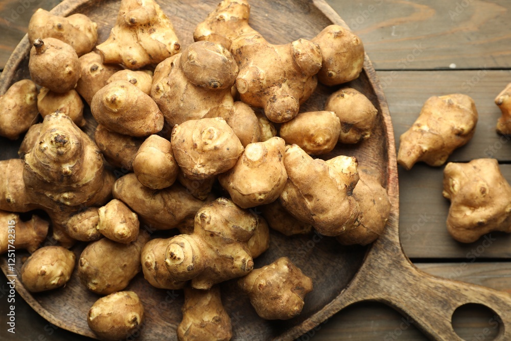 Fototapeta premium Raw Jerusalem artichokes on wooden table, top view