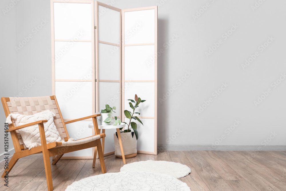 Fototapeta premium Interior of light room with folding screen, armchair and table