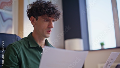 Frustrated entrepreneur reading papers at workplace closeup. Worried businessman