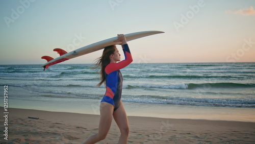 Relaxed sportswoman going sunrise beach carrying surfboard alone. Surf girl