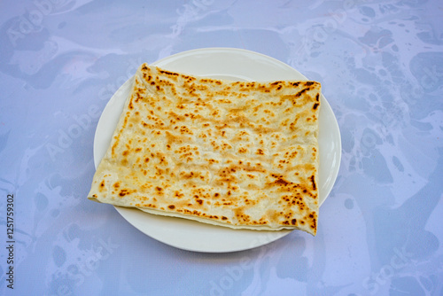 Freshly baked appetizing Turkish tortillas - Gozleme with spinach, cheese  on a white board. Space for text. Handmade Turkish traditional pastries. Ispanakli, otlu peynirli gozleme. Tahinli Katmer photo